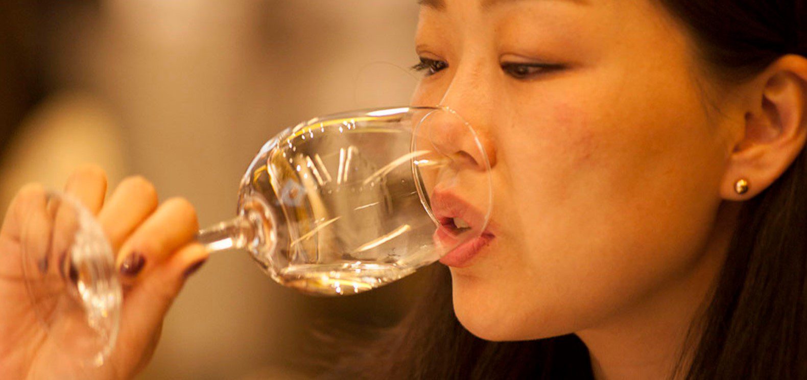 Mulher degusta bebida transparente em taça de vidro no Catad'Or 2021